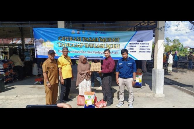 
					Plt Kepala Diskopukmdag Aceh Besar Trizna Darma ST, didampingi Kasi analis perdagangan Diskopukmdag Aceh Besar Abdul Hadi, SE, menyerahkan secara simbolis paket belanja operasi pasar khusus kepada salah seorang pembeli di Kemukiman Lamteuba, Aceh Besar. Foto: Dok. Pemkab Aceh Besar