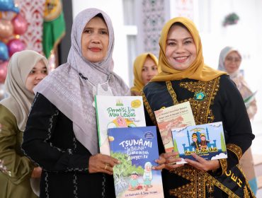 Bunda Paud Aceh, Hj. Safriati, S.Si, M.Si, membaca cerita sekaligus menyerahkan buku Kepada Kepala Sekolah, dalam acara Open House Panggong Anuek Miet, di Pendopo Walikota Banda Aceh, Jumat, 24 Januari 2025.